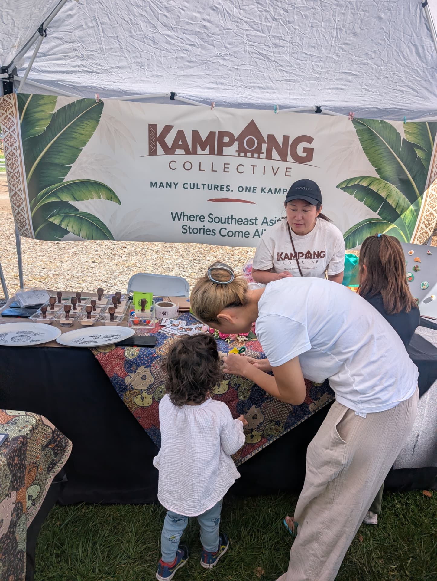 Kampong Collective volunteers and visitors at a hands-on activity beneath the Kampong Collective banner