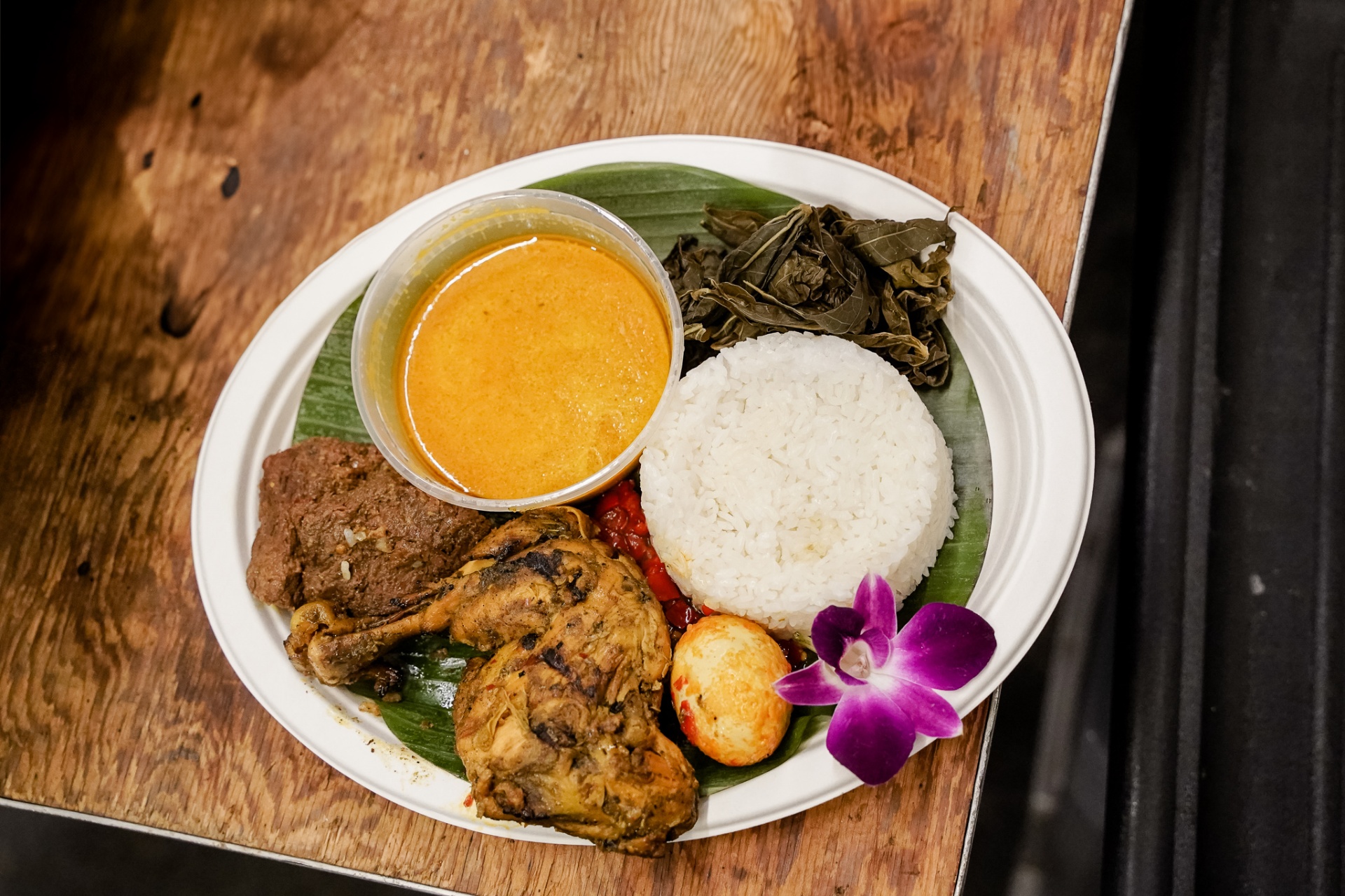 Nasi padang plate with chicken, beef rendang, egg, and curry on banana leaf