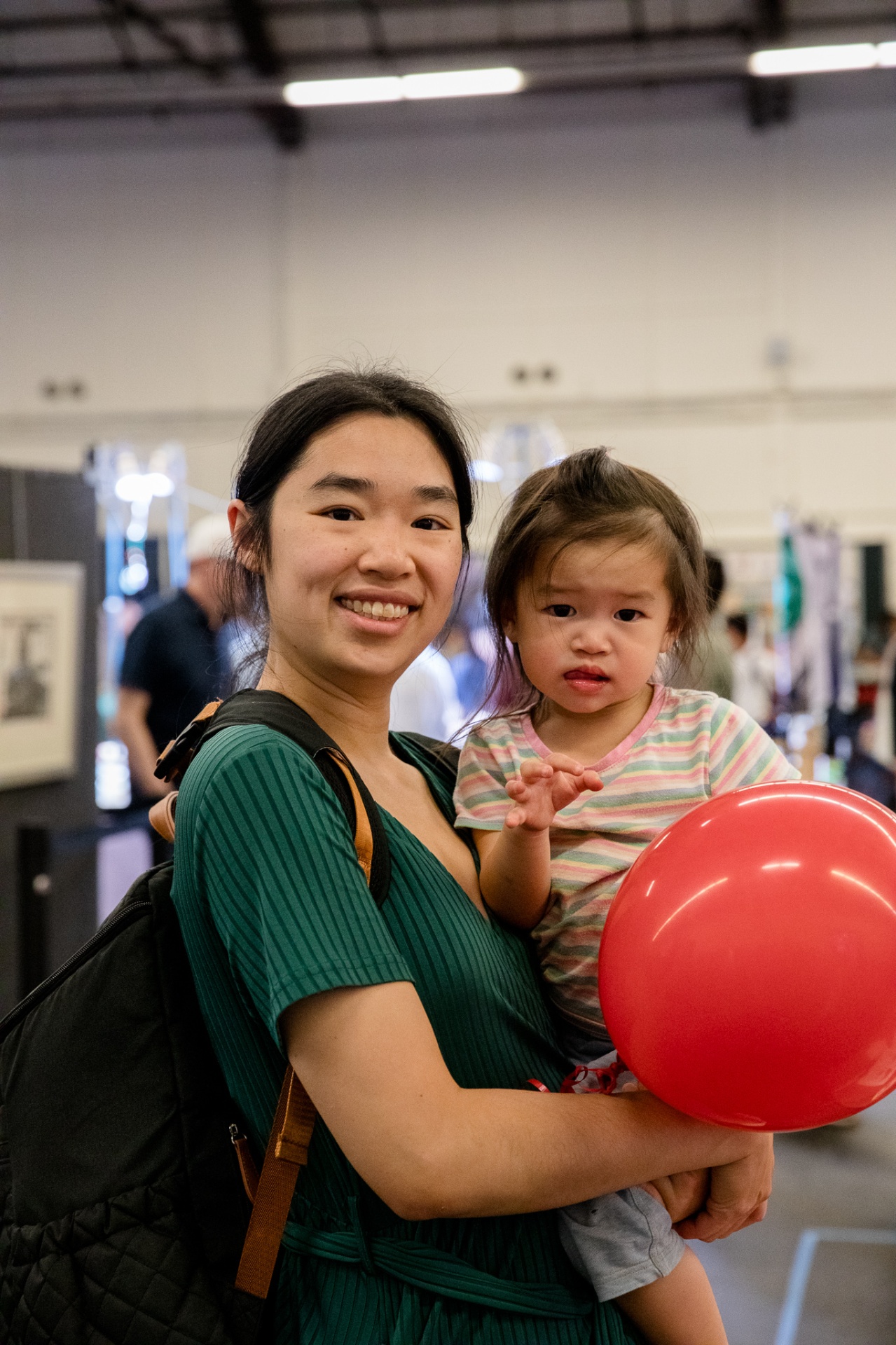 Mother holding daughter with red balloon at the festival